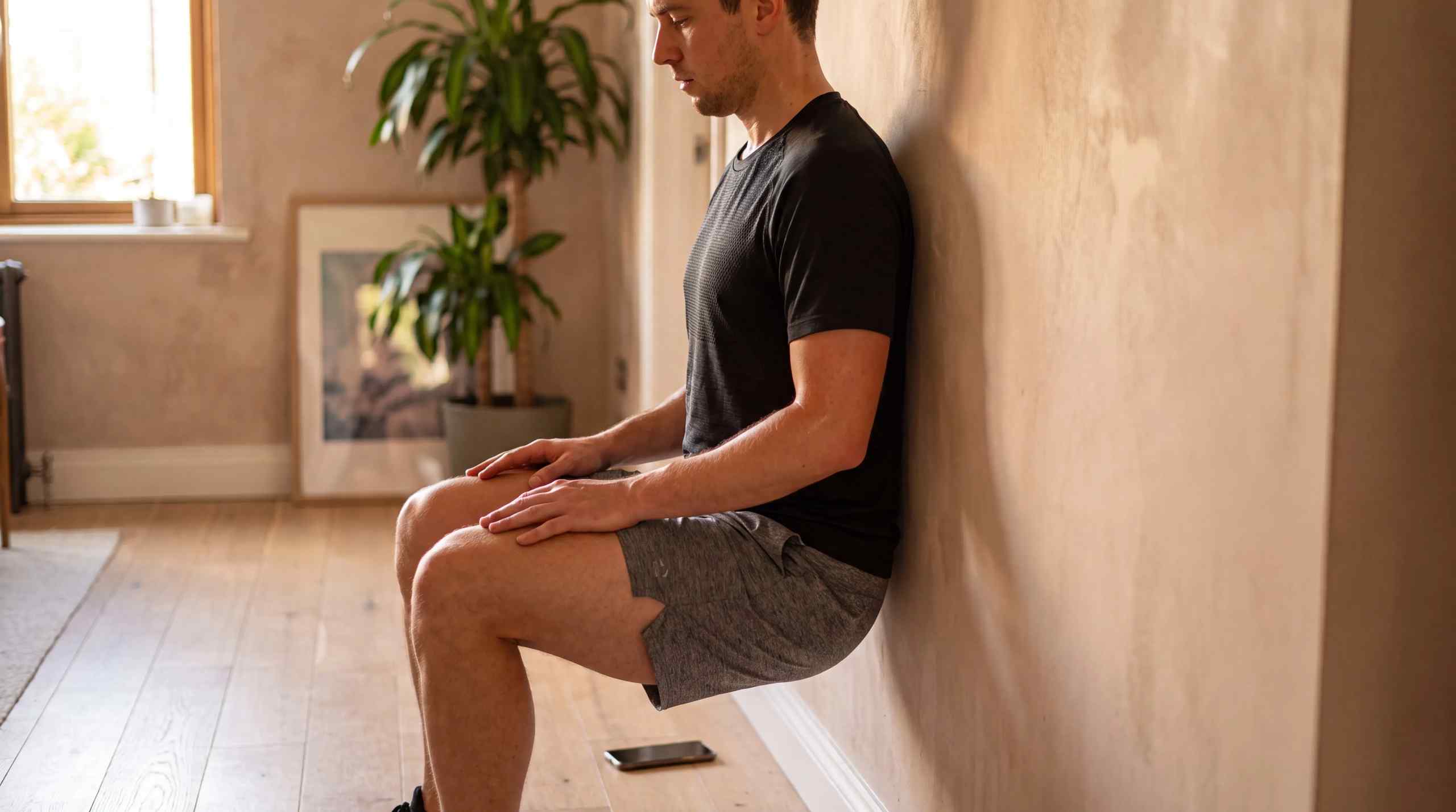 A man performing a wall sit exercise at home.